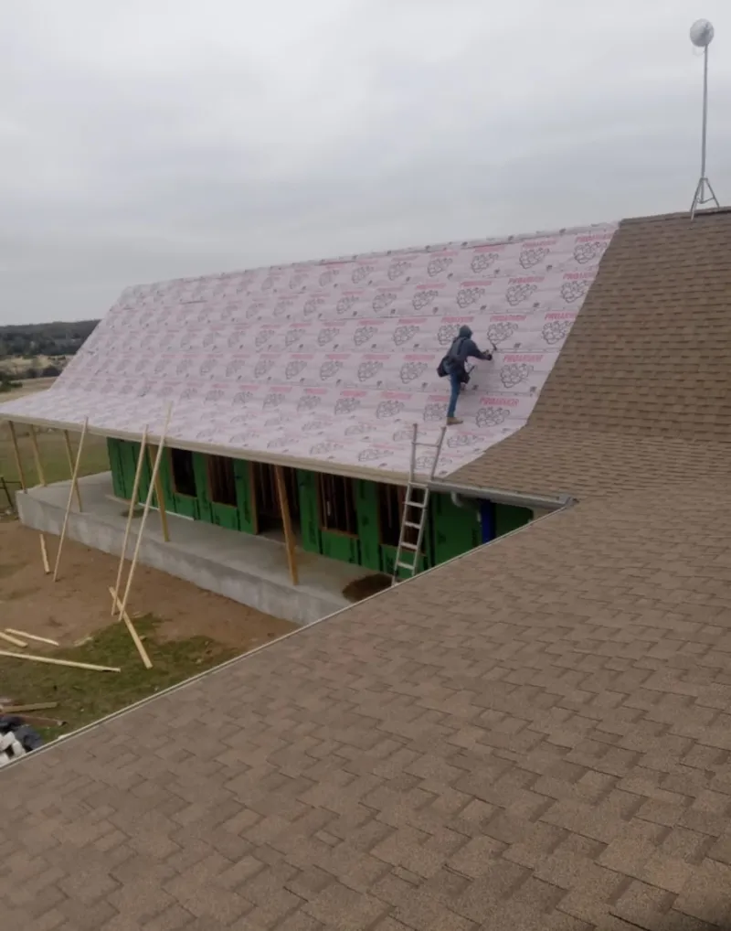 Worker preparing underlayment for a metal roof installation in Crete